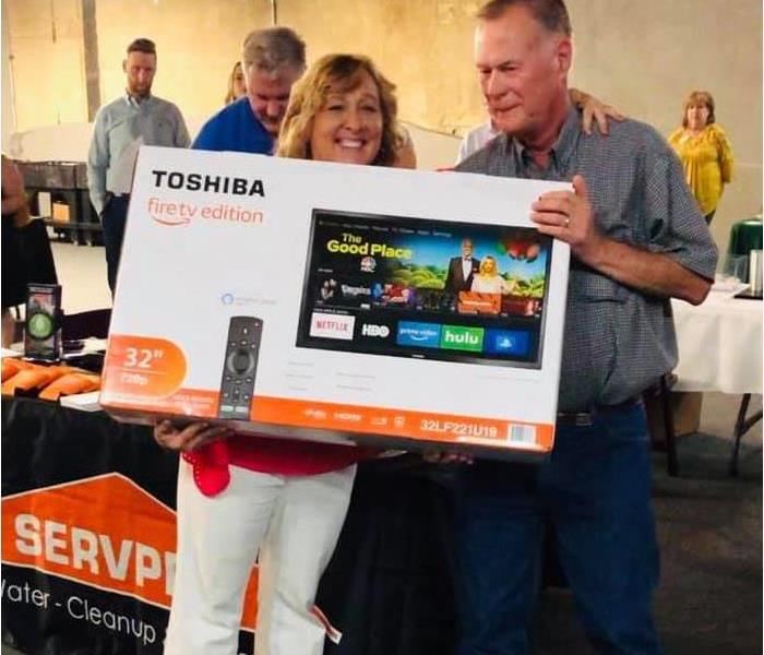 Carolee gives a large screen TV to one lucky winner at an after hours chamber event. 