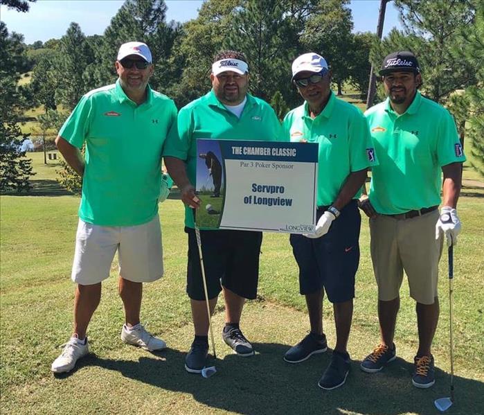 Four golf team members pose for picture holding signage 