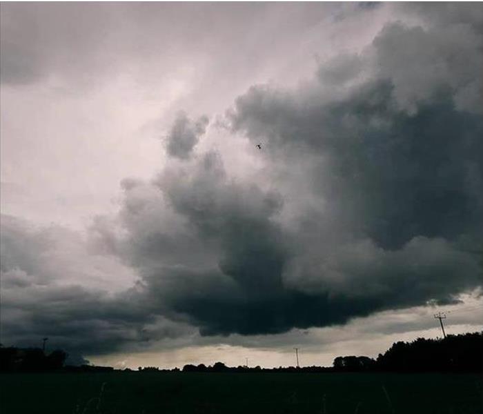 A large storm cloud dropping rain across a empty field.