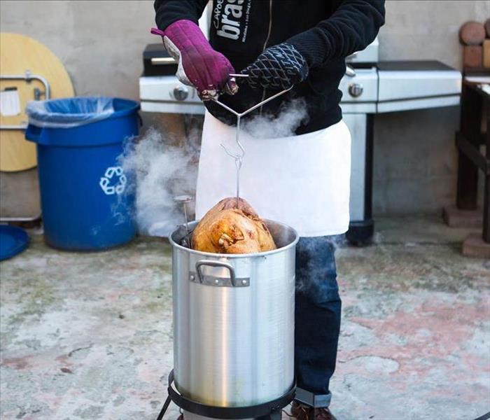 A turkey being lowered into a deep fryer