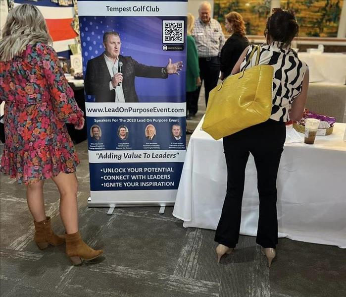 Woman at a table next to a banner for a conferance